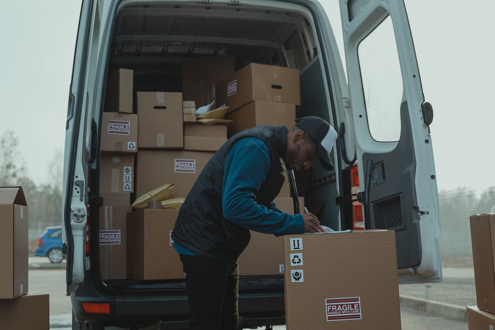 Delivery man sorting packages in van, organizing shipments for distribution.